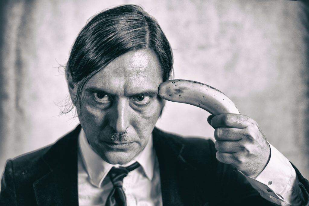 Hombre con un plátano en la sien. Fotografía en blanco y negro de Ada Crow.
