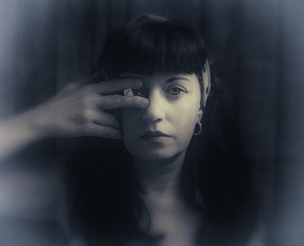 Mujer con dado en un ojo. Fotografía en blanco y negro.
